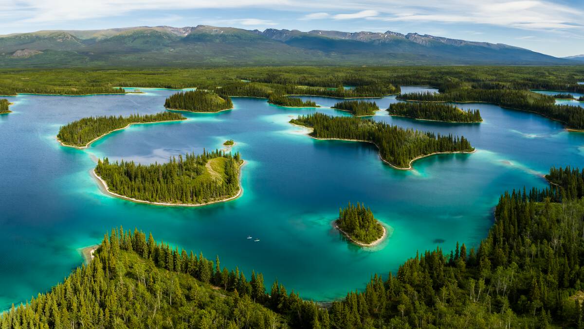 Paddlers glide through a turquoise lake dotted by treed islands.
