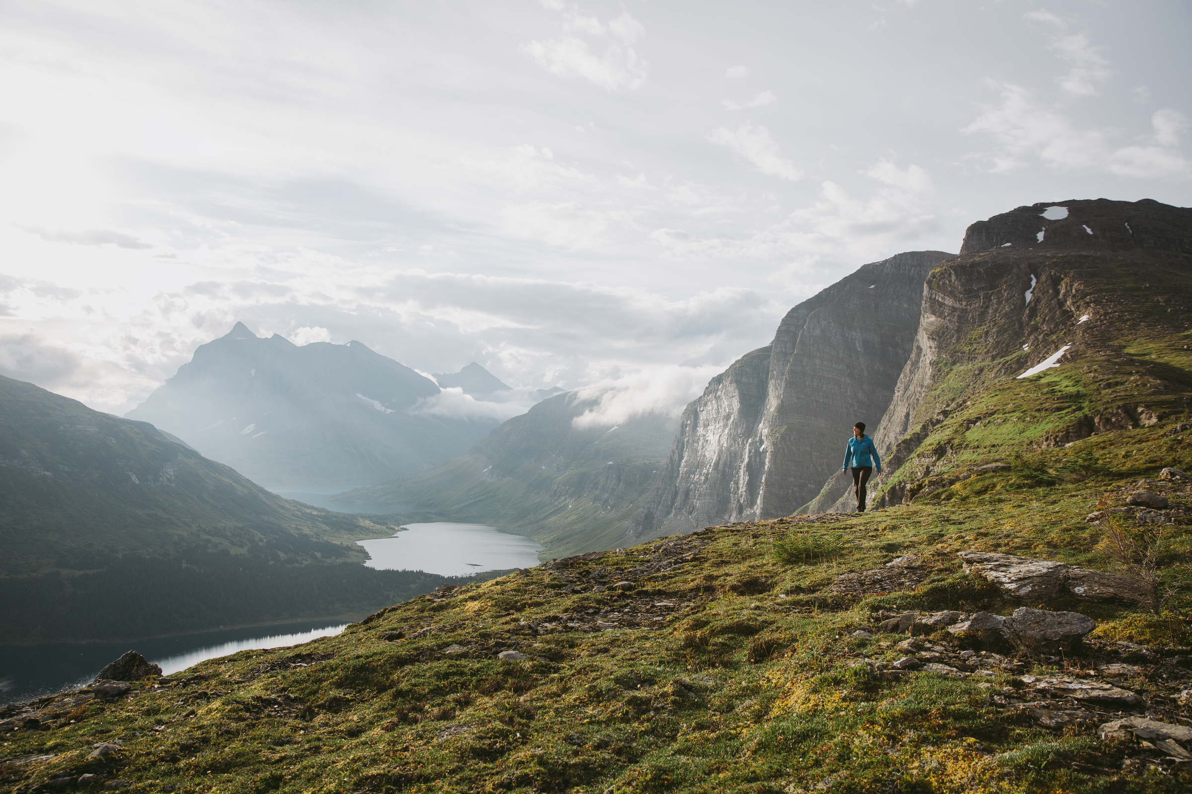 A hiker surrounded by towering mountains and alpine lakes.