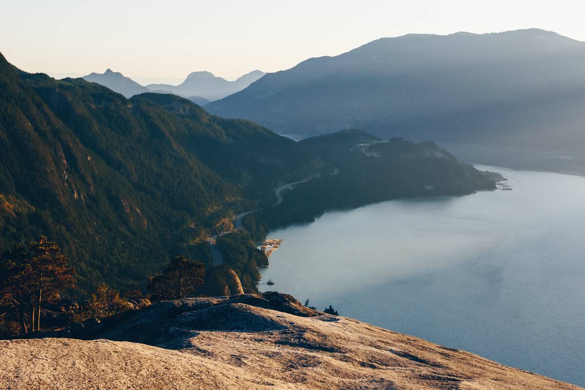 View from the top of a massive granite monolith overlooking ocean and mountains.