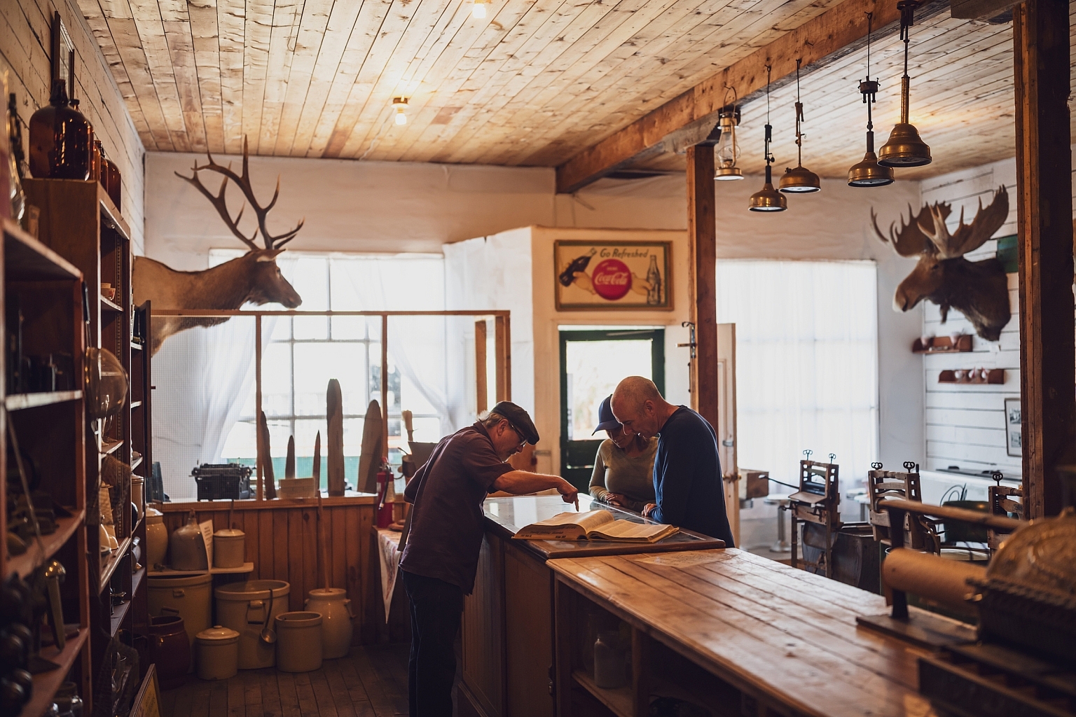 People chatting over the counter in a historic building at Walter Wright Pioneer Village in Dawson Creek, BC.